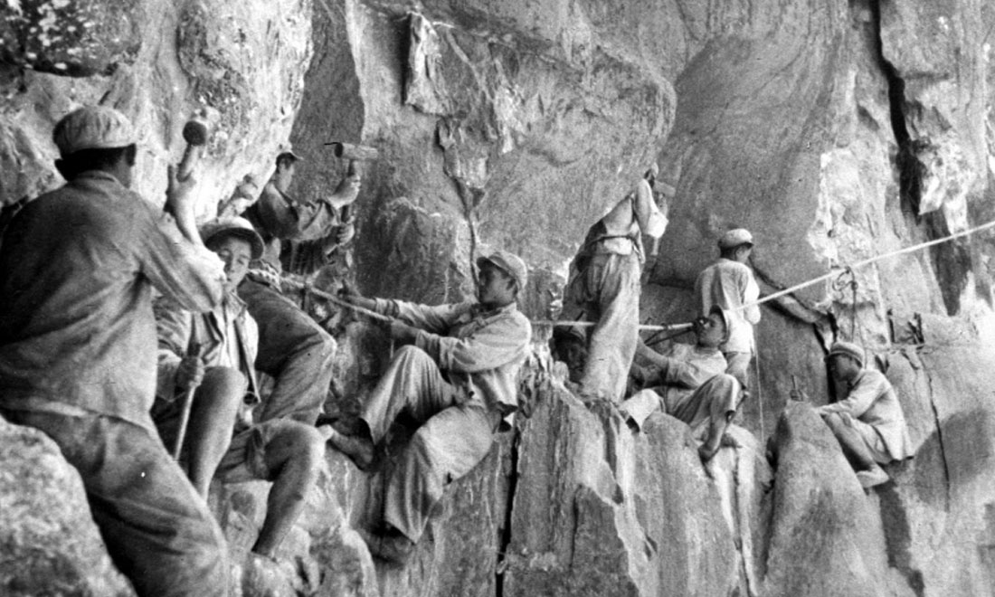 1954年，修筑康藏公路的解放軍戰(zhàn)士們?cè)谂瓋砂兜膽已露副谏媳偕街?。新華社稿 李萬(wàn)春、張加里攝